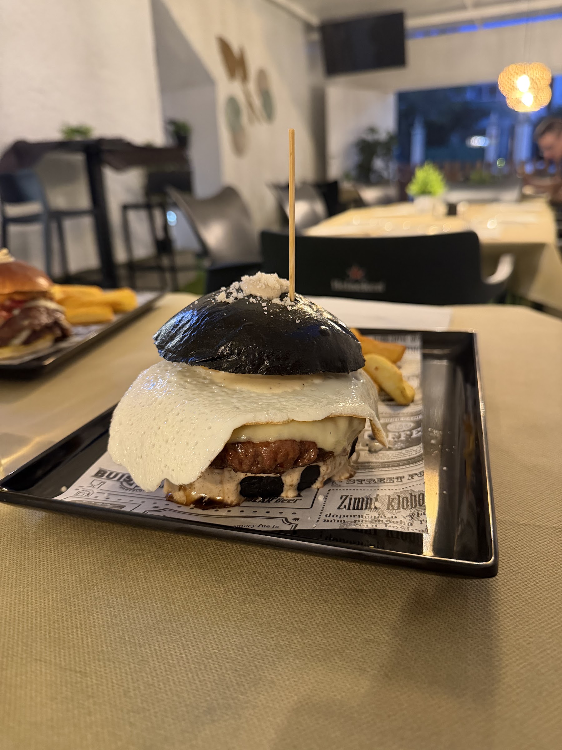 Hamburguesa de pan negro con queso fundido y huevo, servida en el comedor de Cuatrocientosmetros