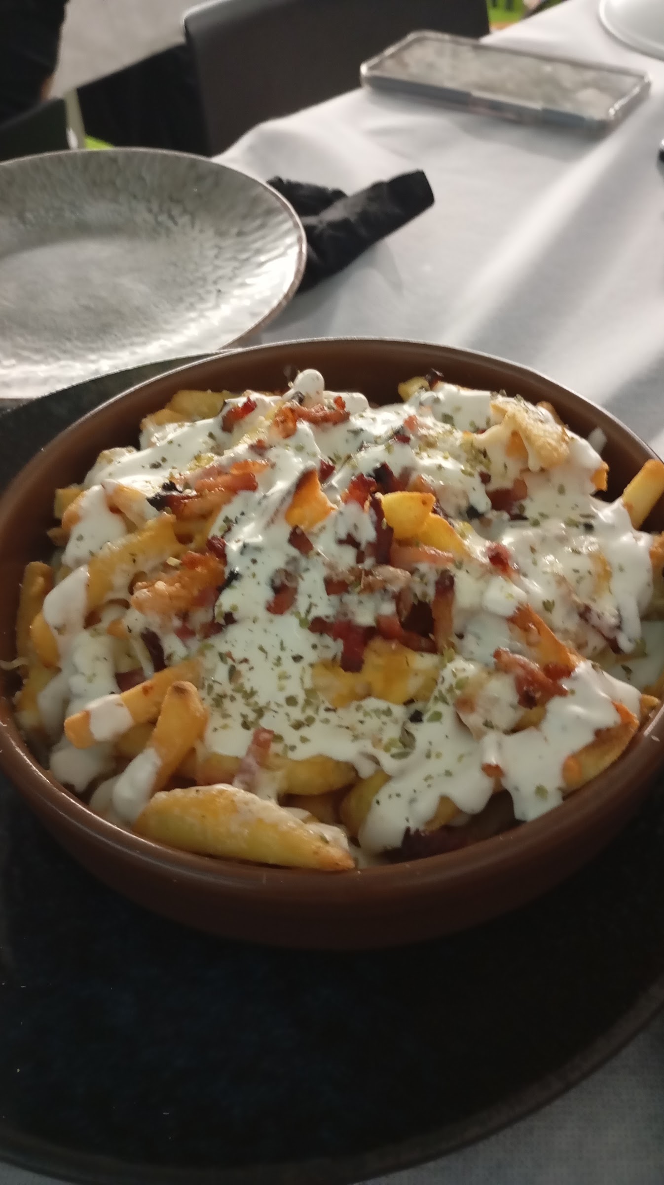 Cazuela de patatas con salsa de queso, bacon y orégano